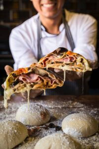 Chef holding stuffed stromboli sliced in two pieces.