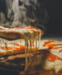 Hot pizza slice with melting cheese on spatula.