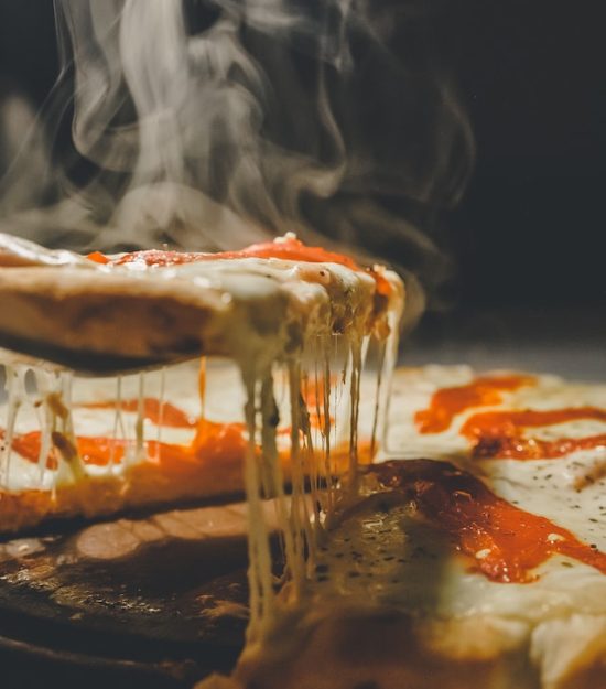 Hot pizza slice with melting cheese on spatula.