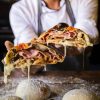 Chef holding stuffed stromboli sliced in two pieces.