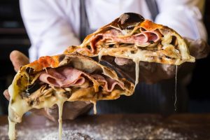 Chef holding stuffed stromboli sliced in two pieces.